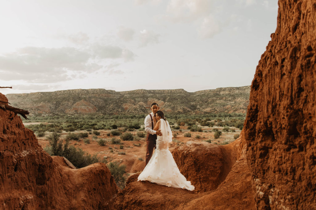 Palo Duro Canyon. bride and groom get ready for fun portraits on red rock at the state park