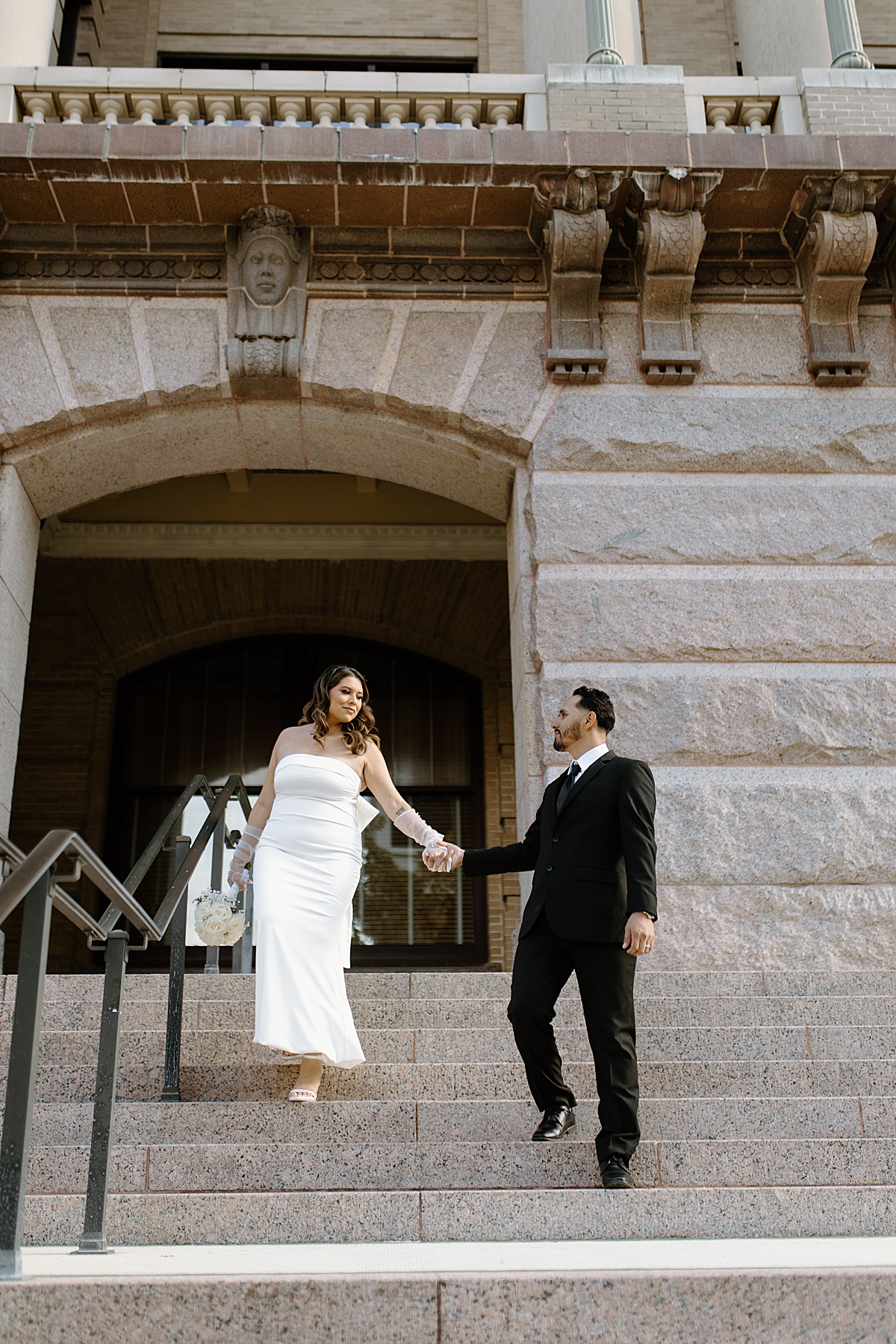 bride and groom being captured walking down the steps of downtown by a Houston elopement photographer