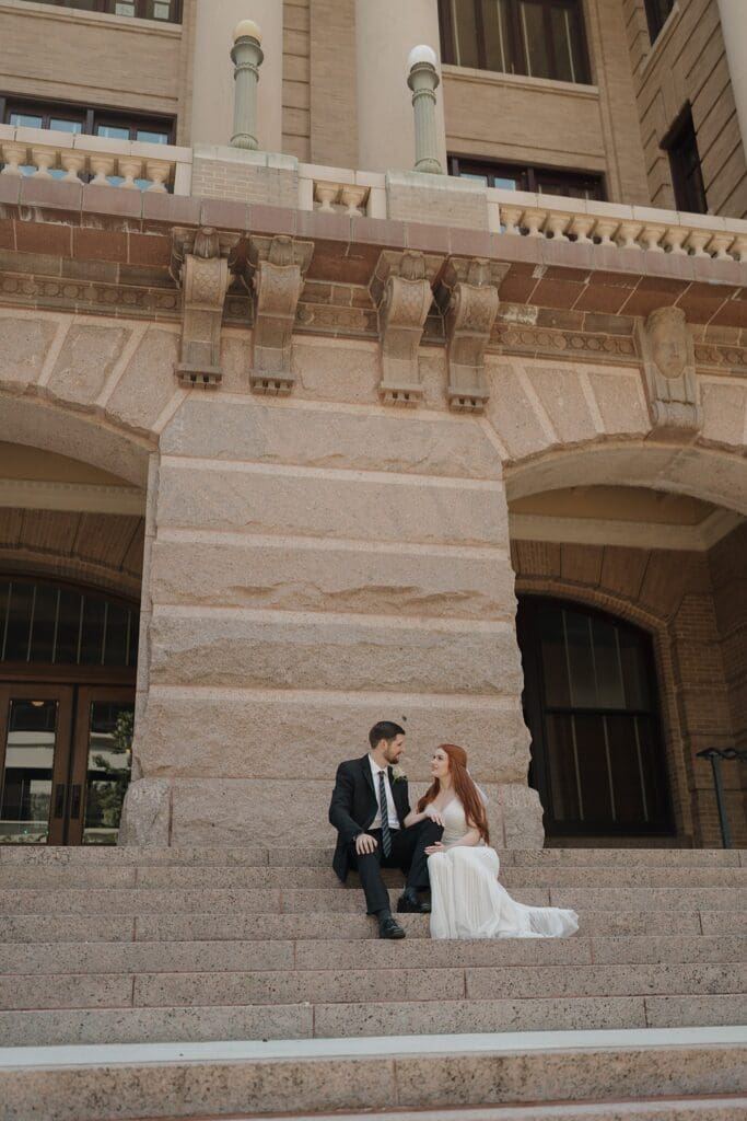 couple sitting on the steps of the courthouse after eloping 